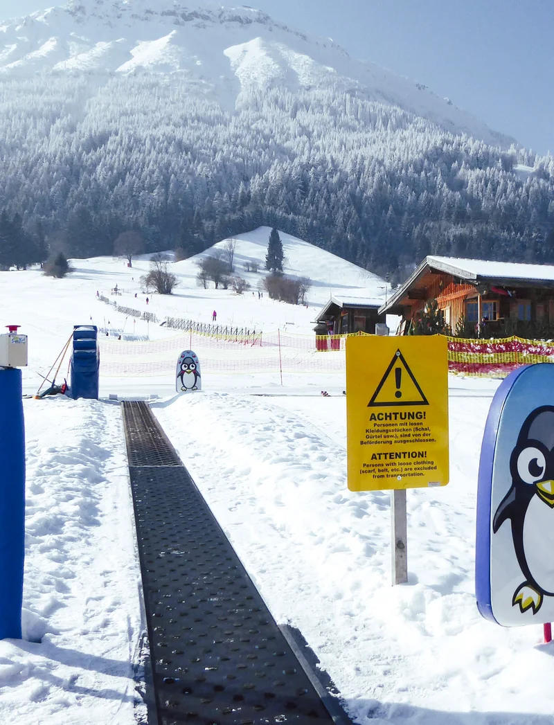 Förderband an der Skipiste mit einer verschneiten Landschaft im Hintergrund.