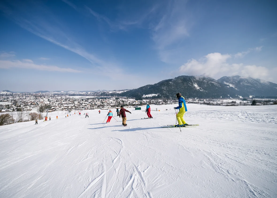 Skifahrer auf der Piste, im Hintergrund ist das verschneite Tal sowie Berge zu erkennen.