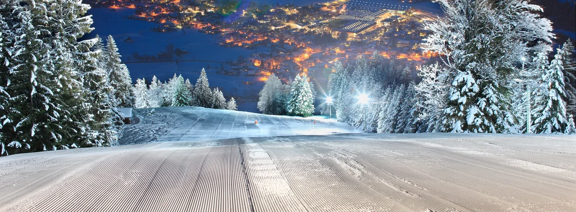 Blick über die beleuchtete Skipiste beim Flutlichtfahren in Pfronten-Steinach mit einem schönen Blick ins Tal.