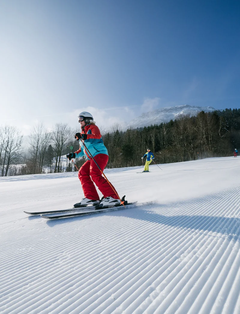 Skifahrer auf der Piste, im Hintergrund eine verschneite Landschaft.
